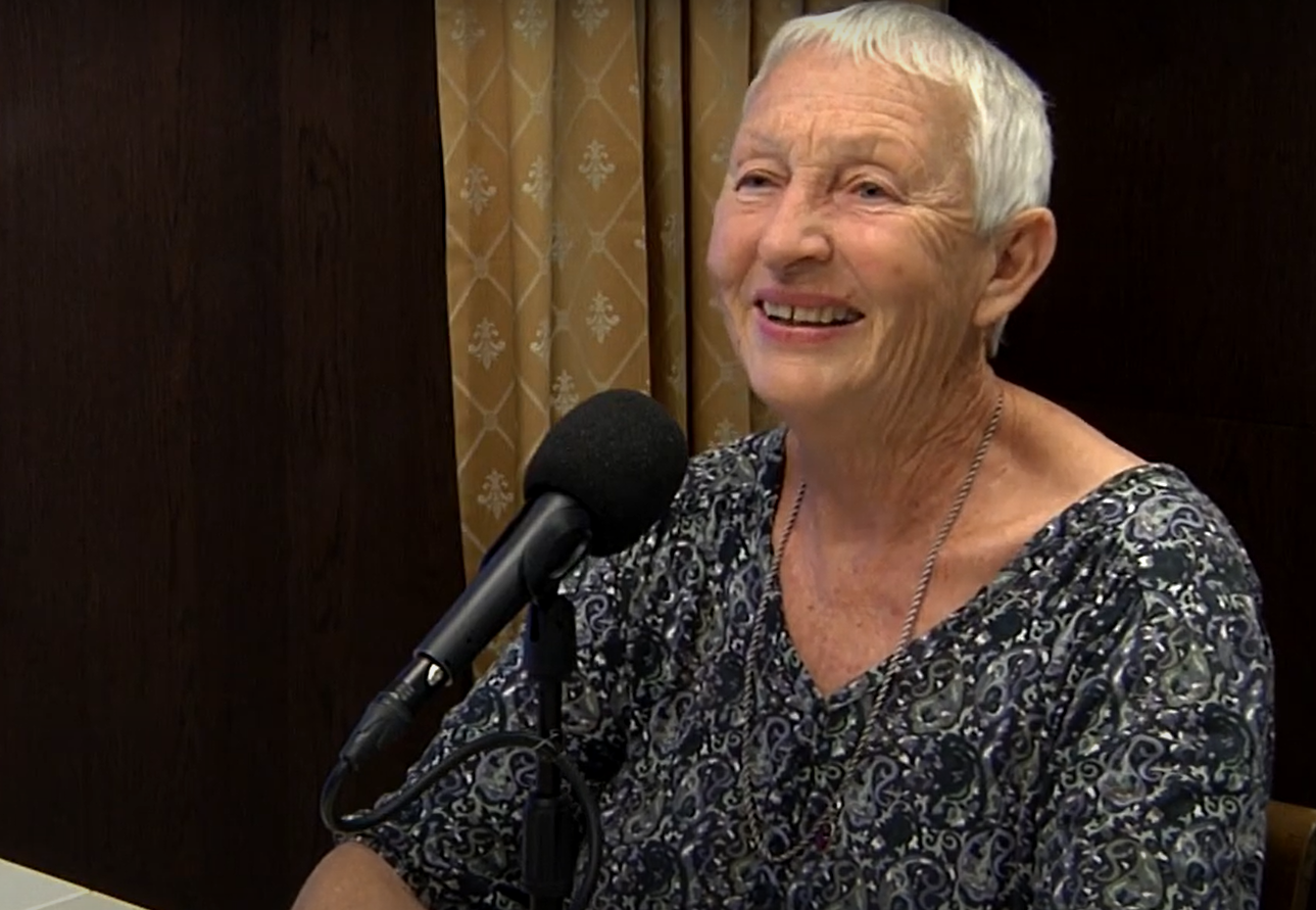 Portrettbilde av Anne Haugen Wagn. Hun smiler foran en mikrofon.